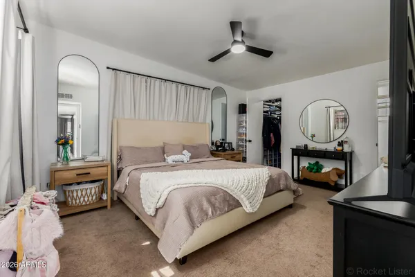 a bedroom with a bed a mirror on dresser and a chandelier