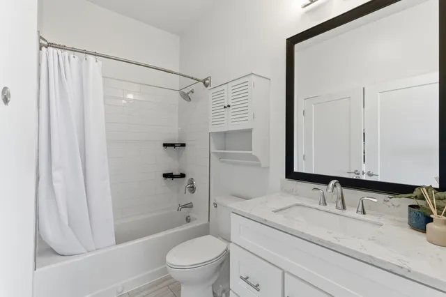 a bathroom with a granite countertop sink a toilet and shower
