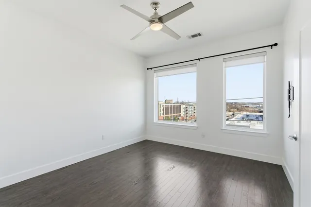an empty room with wooden floor and windows