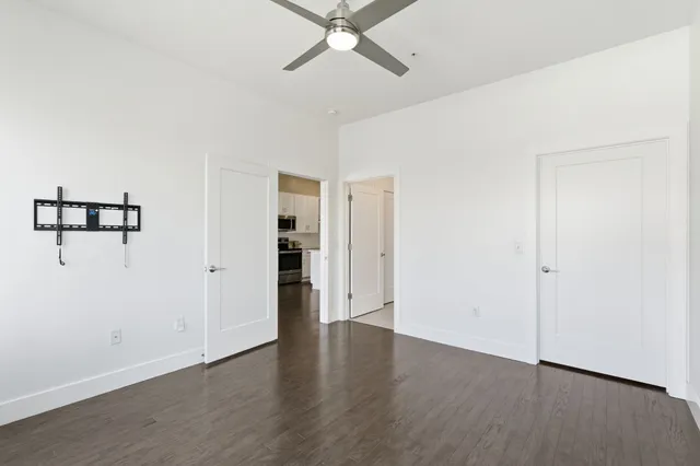 an empty room with a ceiling fan and wooden floor