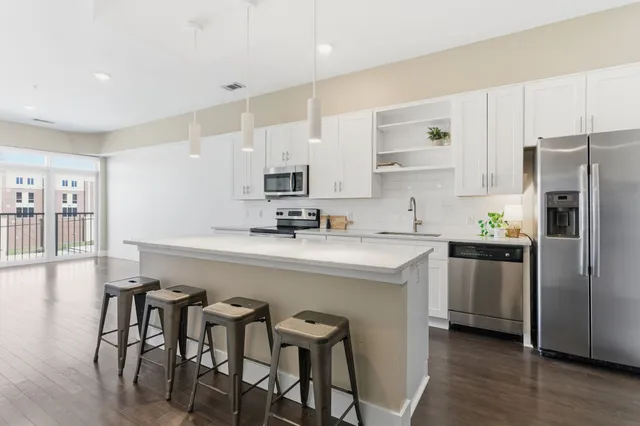 a kitchen with stainless steel appliances a table chairs refrigerator and microwave