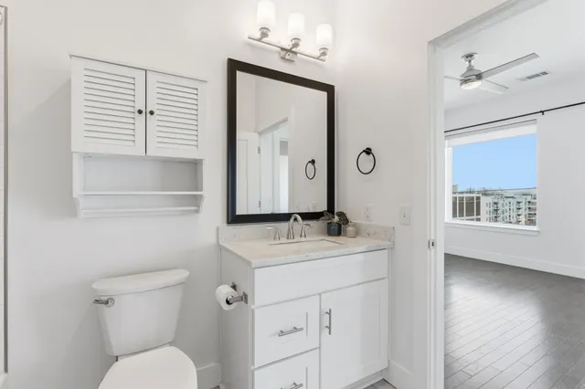 a bathroom with a granite countertop sink toilet and mirror