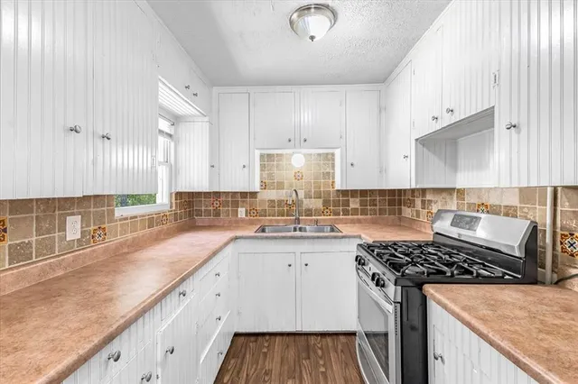 a kitchen with granite countertop a sink stove and cabinets