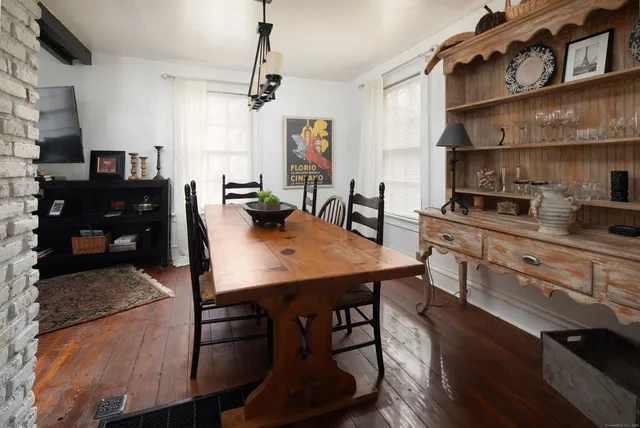 a kitchen with stainless steel appliances granite countertop a stove a refrigerator a sink a dining table and chairs with wooden floor