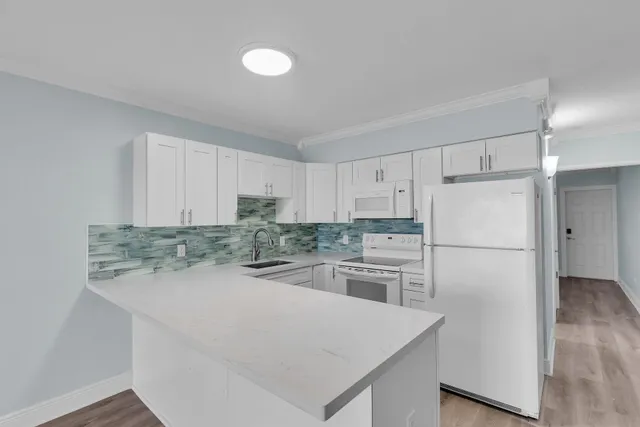 a kitchen with a refrigerator a stove top oven a sink and white cabinets