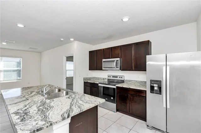 a kitchen with stainless steel appliances kitchen island granite countertop a refrigerator and a stove top oven