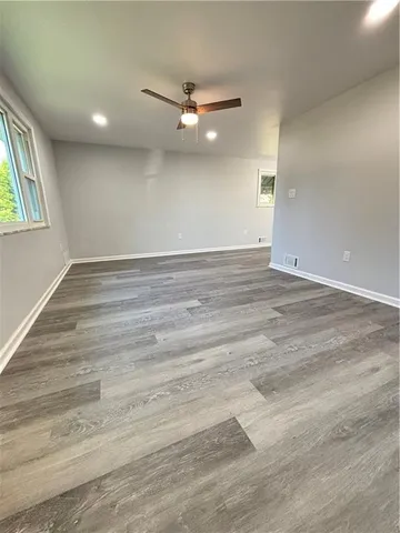 an empty room with wooden floor and windows