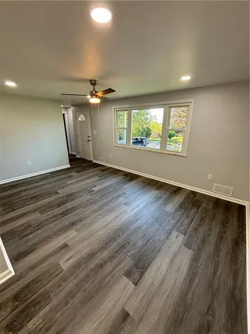 an empty room with wooden floor chandelier and windows