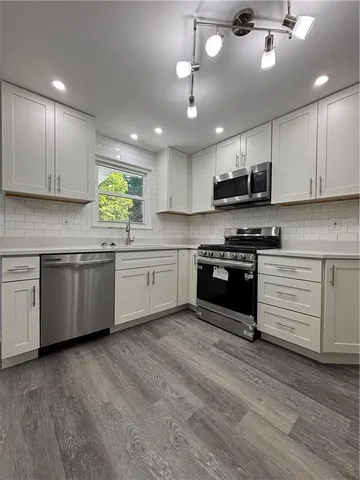 a kitchen with stainless steel appliances granite countertop a stove top oven a sink dishwasher and a refrigerator