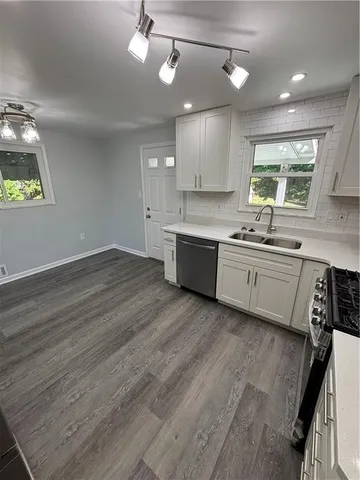 a large kitchen with stainless steel appliances granite countertop a sink dishwasher a stove and white countertops with wooden floor