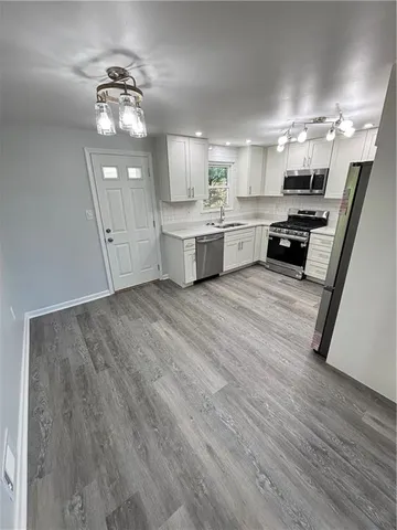 a large white kitchen with cabinets a sink and appliances