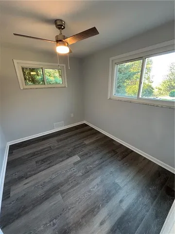 an empty room with wooden floor fan and windows