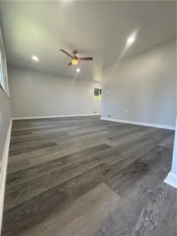 an empty room with wooden floor fan and windows