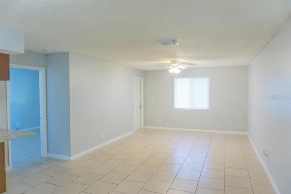a view of an empty room with window and chandelier fan