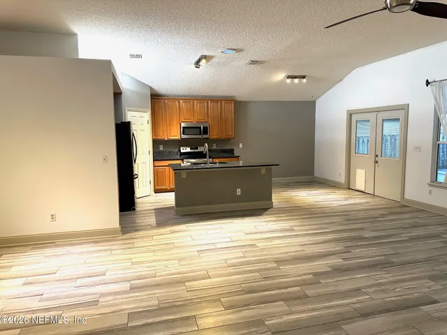 a view of kitchen with stainless steel appliances wooden floor and refrigerator