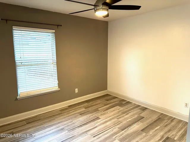 an empty room with wooden floor closet and windows