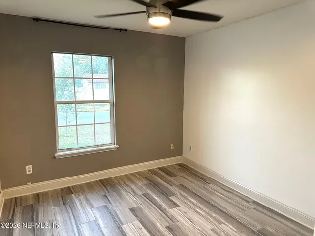 an empty room with a window and ceiling fan