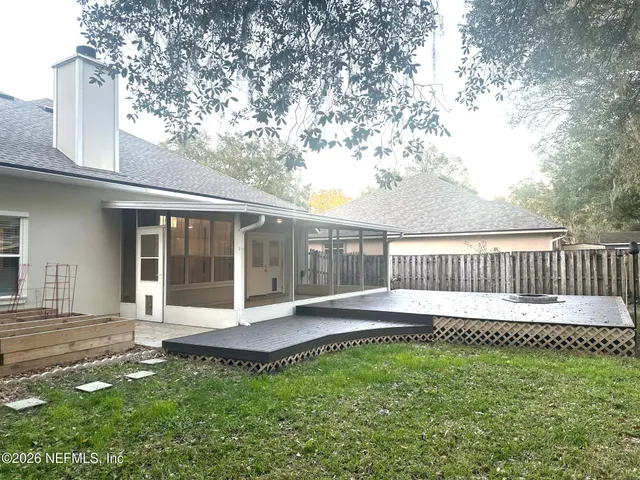 a view of a backyard with wooden fence and large trees