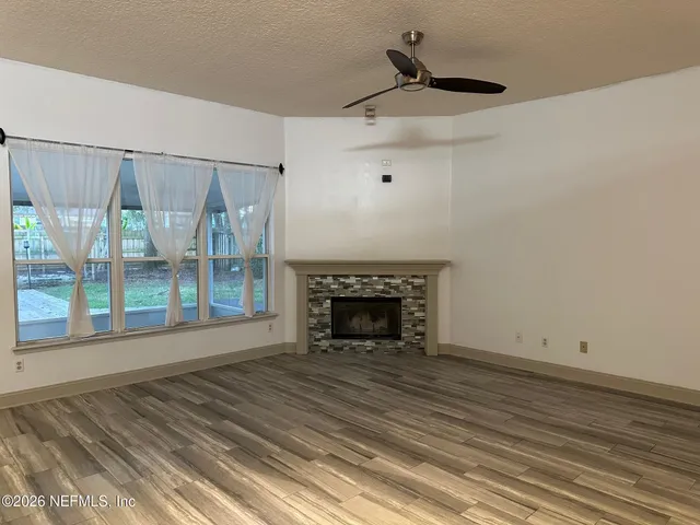 a view of wooden floor fire place and windows in a room