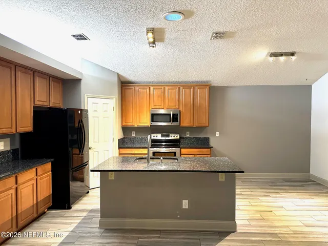 a kitchen with kitchen island granite countertop a refrigerator cabinets and wooden floor