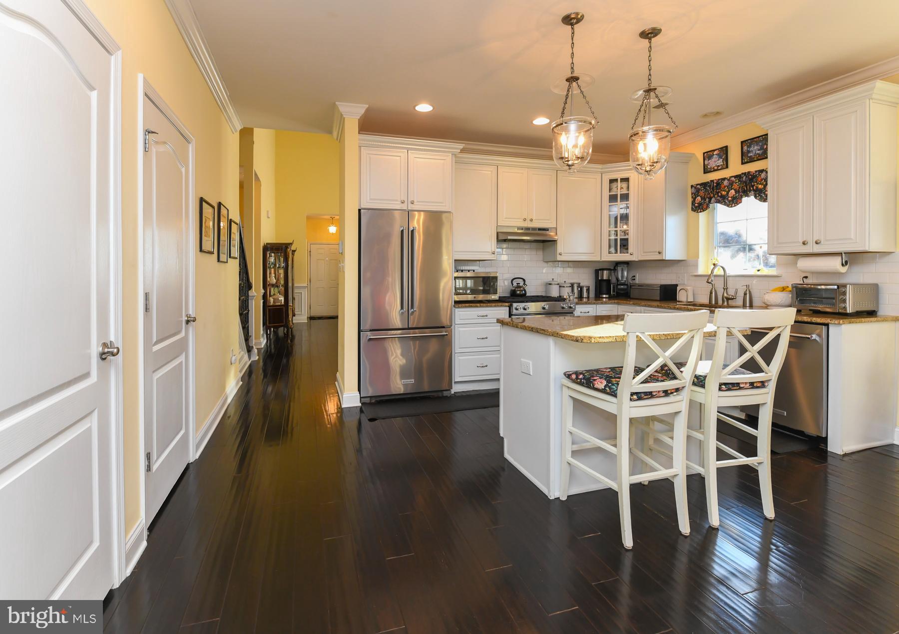 111 Weatherby Lane Glassboro, NJ 08028 - Photo 21 of 95 a kitchen with stainless steel appliances kitchen island granite countertop a refrigerator a stove a microwave oven a dining table and chairs with wooden floor