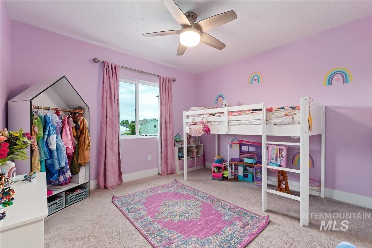 815 Knowledge Street Middleton, ID 83644 - Photo 36 of 49 Spacious room featuring a ceiling fan with integrated lighting, a double window with vertical blinds and drapery, neutral carpet flooring, and a wide baseboard trim