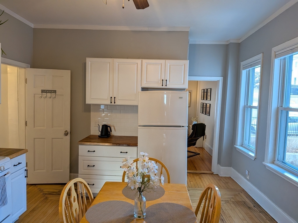 82 Gladstone Street, Unit 2 Boston, MA 02128 - Photo 8 of 23 a kitchen with stainless steel appliances a refrigerator a stove a dining table and chairs with wooden floor