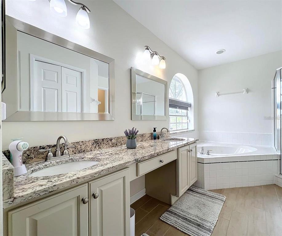 17528 East Apshawa Road Minneola, FL 34715 - Photo 6 of 22 a bathroom with a granite countertop sink mirror and bathtub