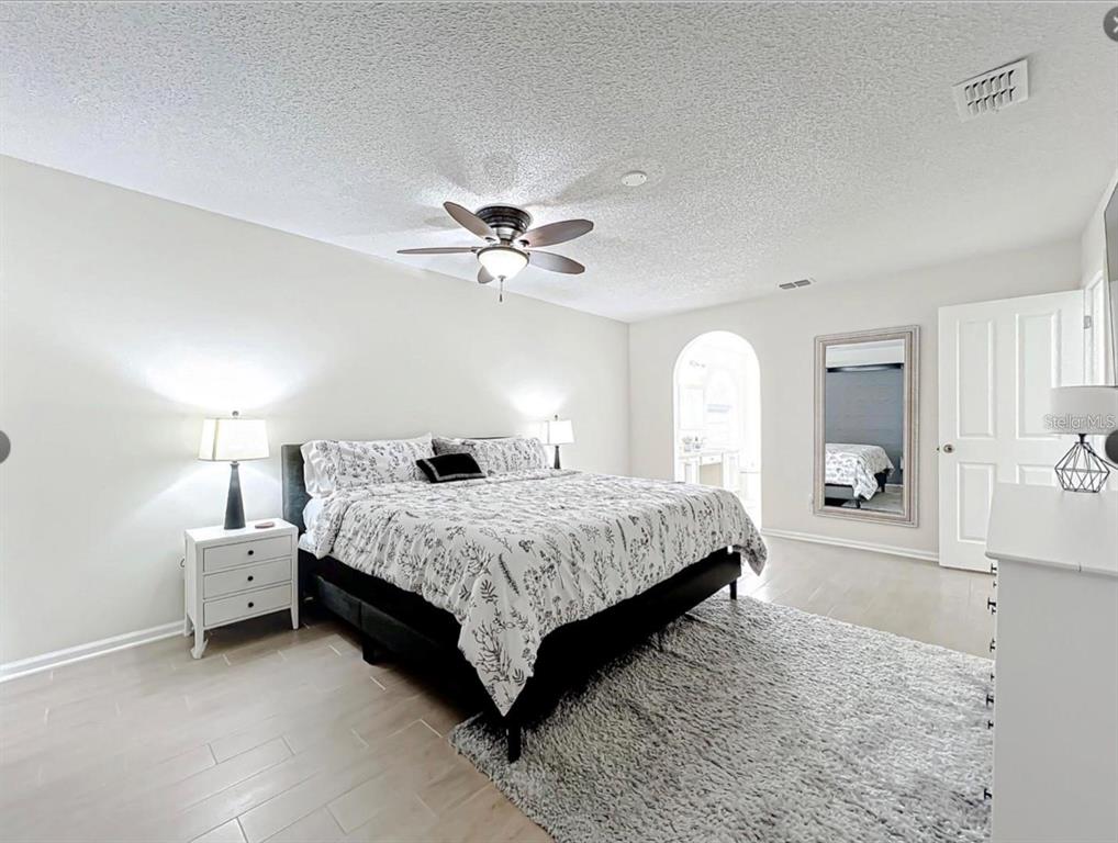 17528 East Apshawa Road Minneola, FL 34715 - Photo 7 of 22 a spacious bedroom with a bed a window and a lamp