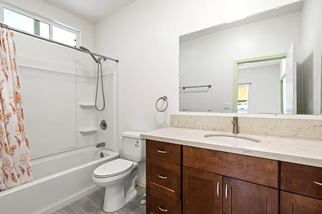 a bathroom with a granite countertop sink a toilet a mirror and shower