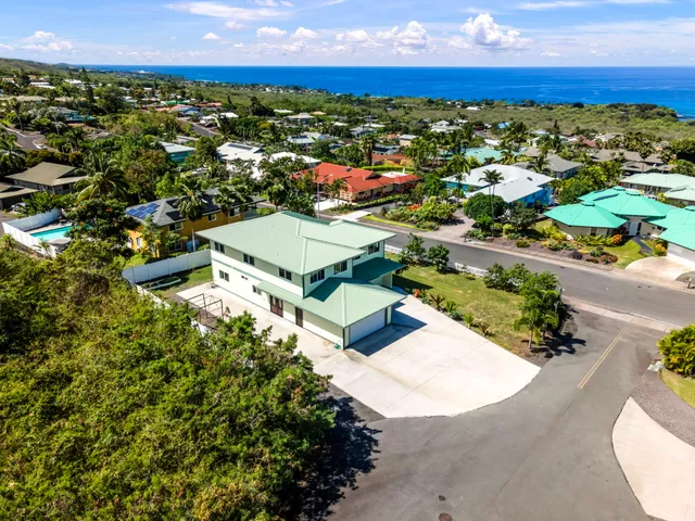 a view of a white house with a big yard and potted plants