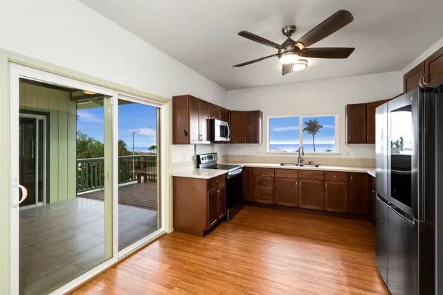 a view of an empty room with wooden floor and a ceiling fan