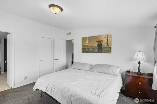 a bedroom with a bed and a lamp on dresser