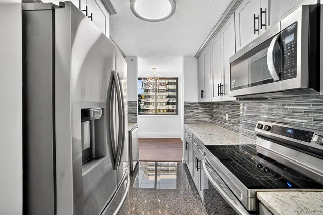 a kitchen with stainless steel appliances granite countertop a refrigerator a stove and a sink
