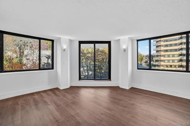 a view of an empty room with window and wooden floor