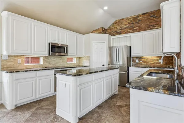 a kitchen with stainless steel appliances granite countertop a sink stove refrigerator and cabinets