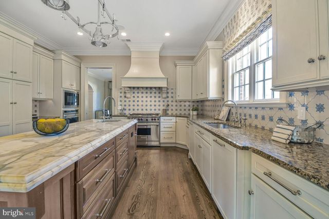 a kitchen with stainless steel appliances granite countertop wooden floors and white cabinets