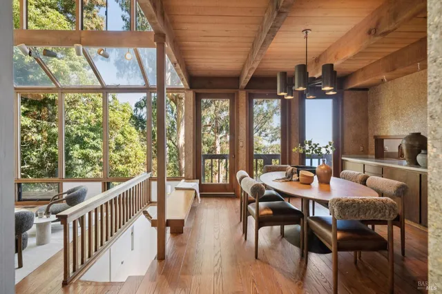 a dining room with furniture large windows and wooden floor