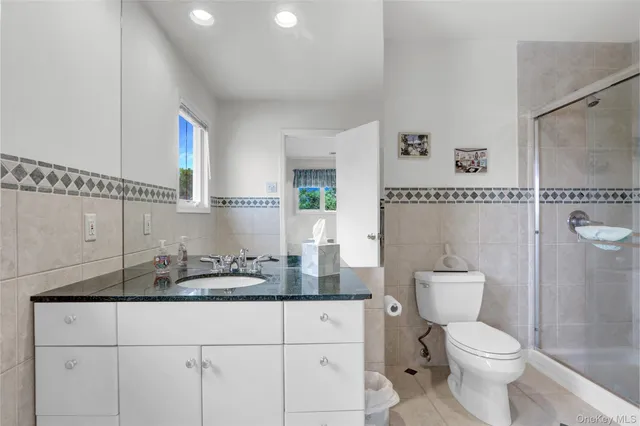 a bathroom with a granite countertop sink mirror vanity and toilet