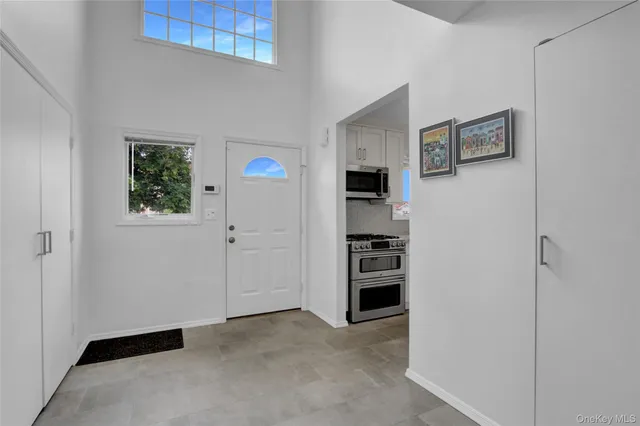 a view of a kitchen with an entryway and white cabinets