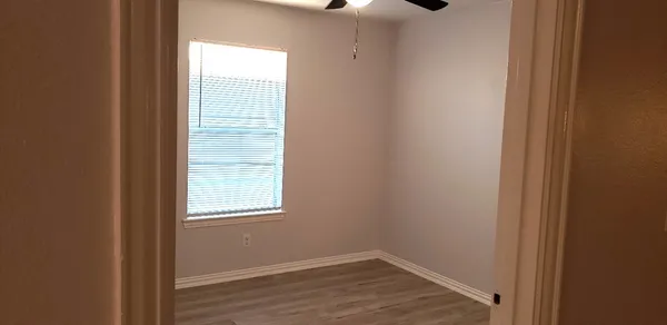 a view of an empty room with wooden floor and a window