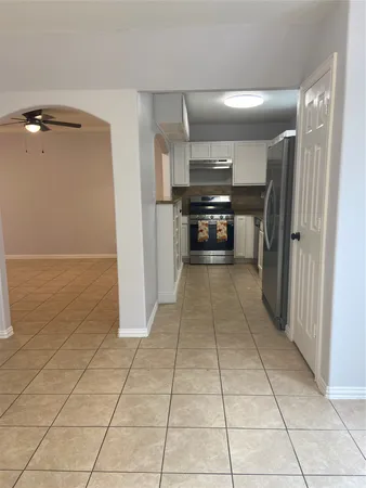 a view of a refrigerator in kitchen and an empty room in wooden floor