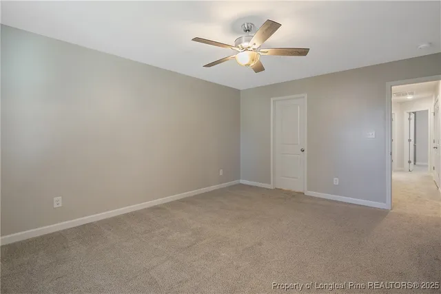 an empty room with a chandelier fan and windows