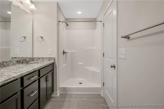 a bathroom with a granite countertop sink a shower and a mirror