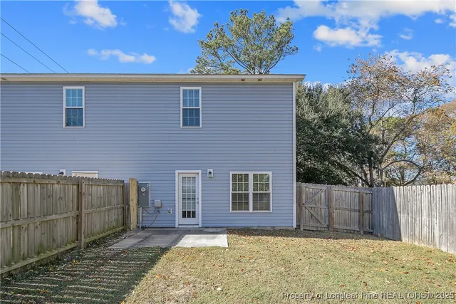 a view of a house with a backyard and wooden fence