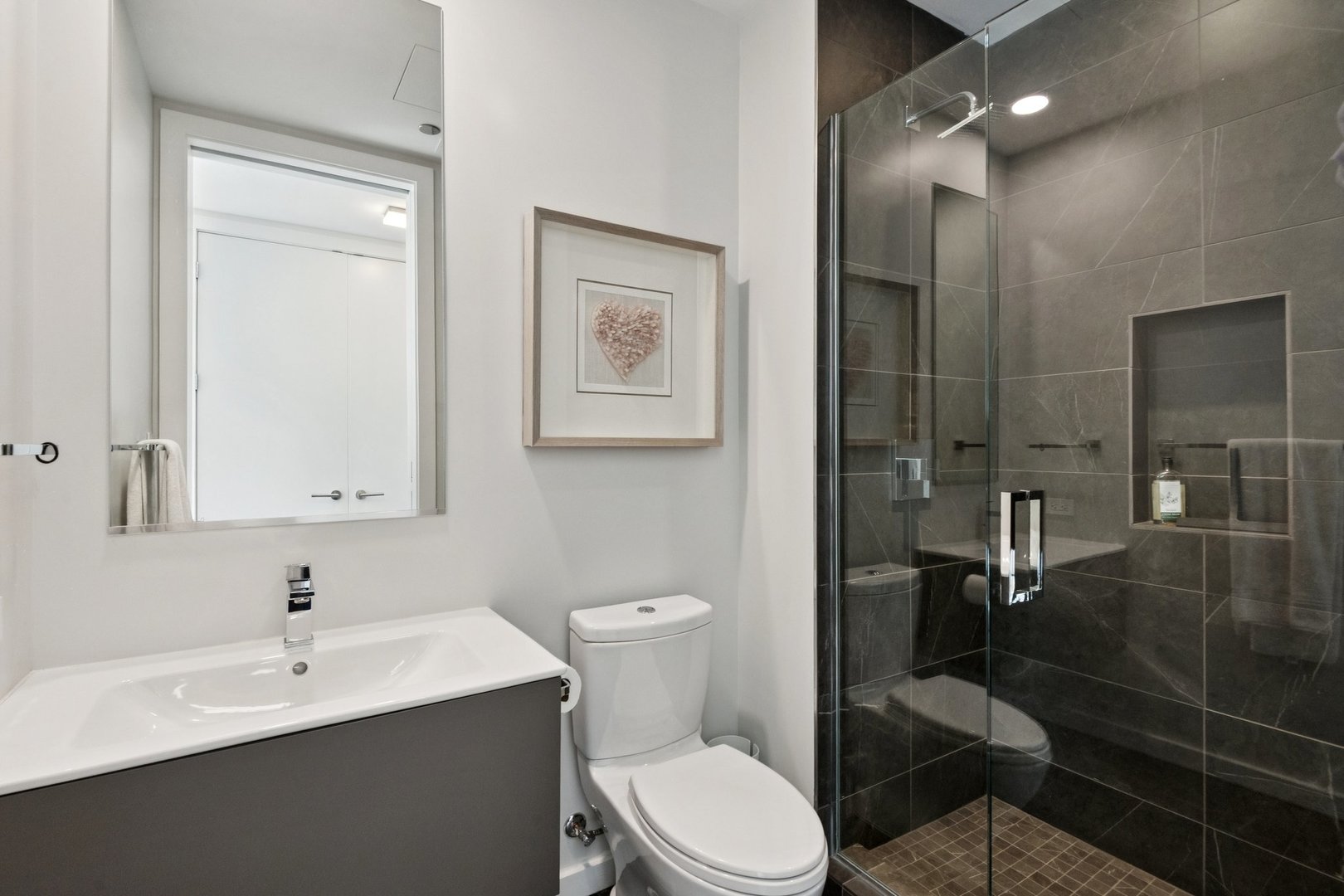 56 West Huron Street, Unit 9 Chicago, IL 60654 - Photo 32 of 38 a bathroom with a toilet a sink a mirror and a shower
