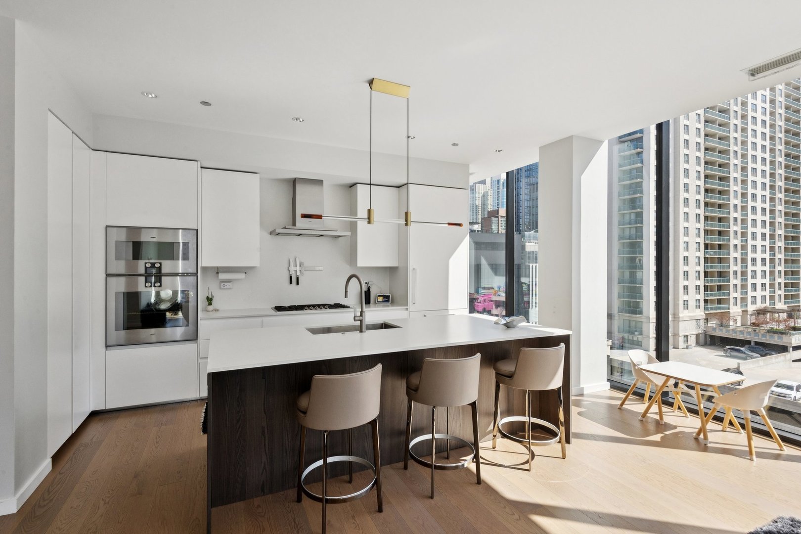 56 West Huron Street, Unit 9 Chicago, IL 60654 - Photo 8 of 38 a kitchen with stainless steel appliances kitchen island granite countertop a table chairs in it and wooden floors