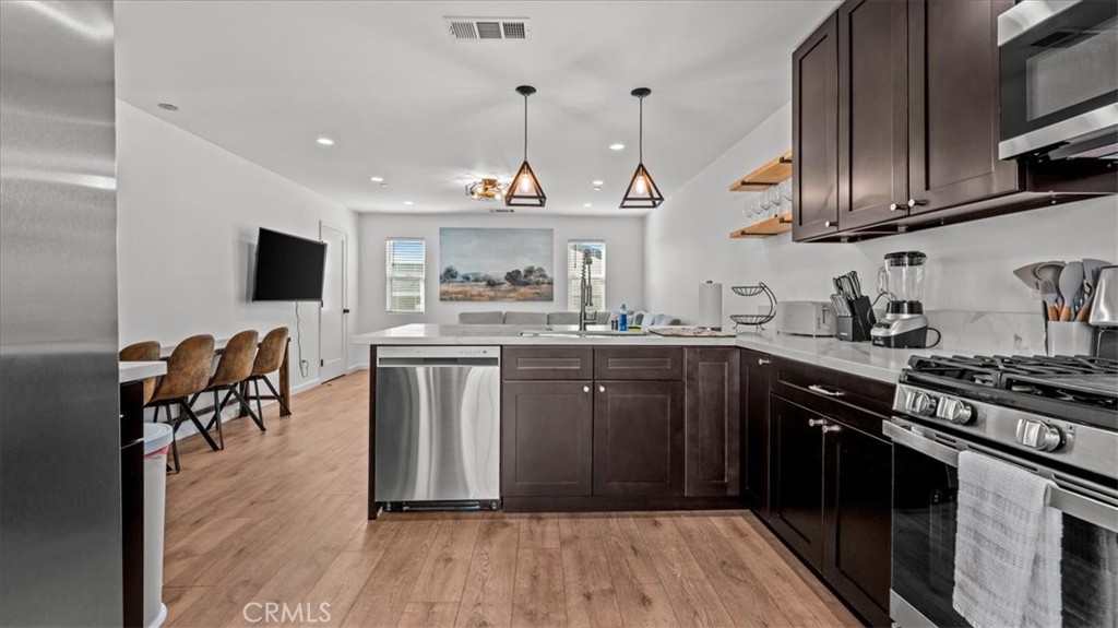 1475 North Holly Avenue Colton, CA 92324 - Photo 9 of 45 a kitchen with stainless steel appliances granite countertop a refrigerator a stove top oven a sink dishwasher and white cabinets with wooden floor