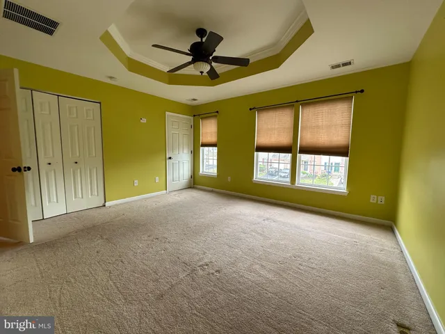 a view of a livingroom with a ceiling fan & windows
