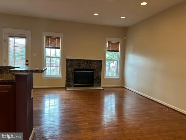 an empty room with wooden floor fireplace and windows